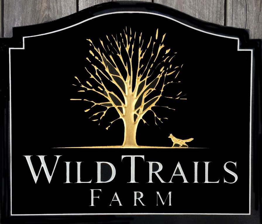 una señal para una granja de vida silvestre con un árbol y un pájaro en Wild Trails Farm, en Springfield
