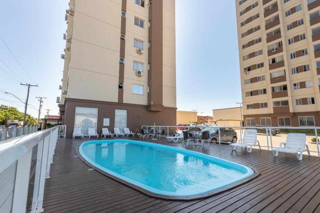 a swimming pool on a deck with chairs and a building at Apartamento em ótima localização in Torres