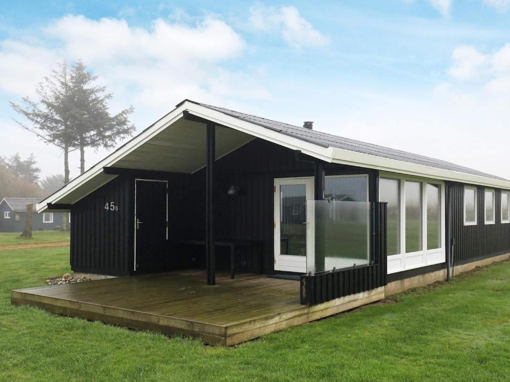 a black house with a wooden deck in a field at 6 person holiday home in Vinderup in Vinderup