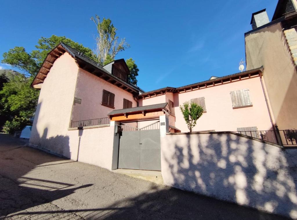une maison blanche avec un portail et un garage dans l'établissement CASA PELAIRE - Wifi, barbacoa, pistas 4 min a pie, à Panticosa