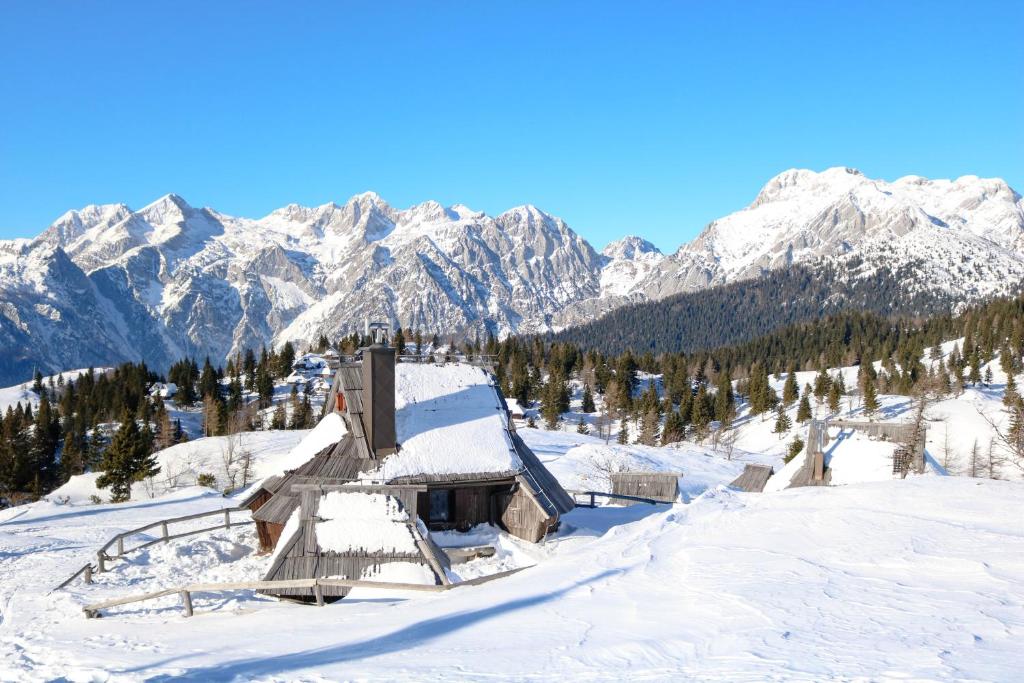 a cabin in the snow with mountains in the background at CHALET Kocna - I FEEL ALPS in Stahovica