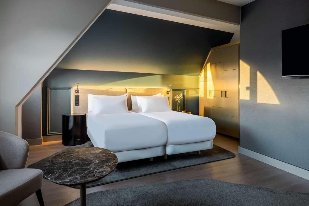 
a white bed sitting in a living room next to a window at NH Collection Salzburg City in Salzburg
