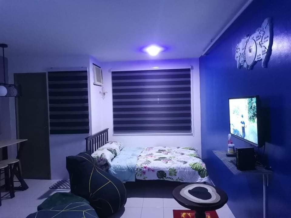 a blue room with a bed and a tv at Chichi's Snug Pad near Enchanted Kingdom and Nuvali in Santa Rosa