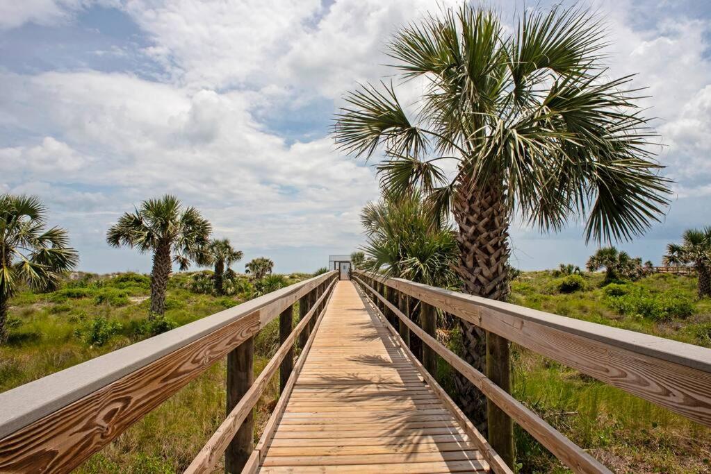 un puente de madera con una palmera. en Beach Condo Getaway en Saint Augustine