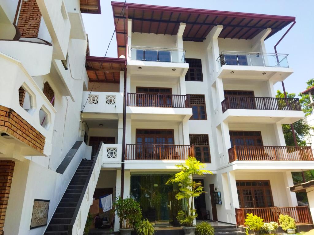 a large white building with balconies and trees at Shanika Beach Inn in Tangalle