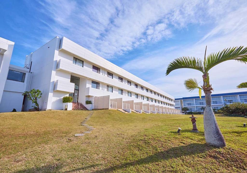 a building with a palm tree in front of it at Royal View Hotel Churaumi in Motobu