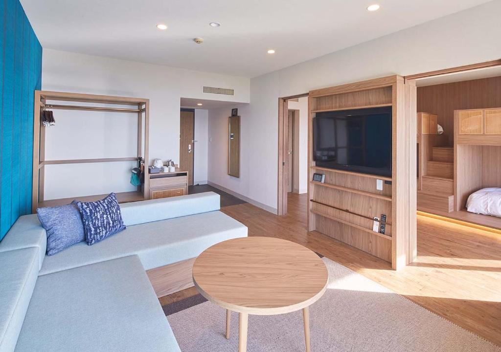 a living room with a couch and a table and a tv at Royal View Hotel Churaumi in Motobu