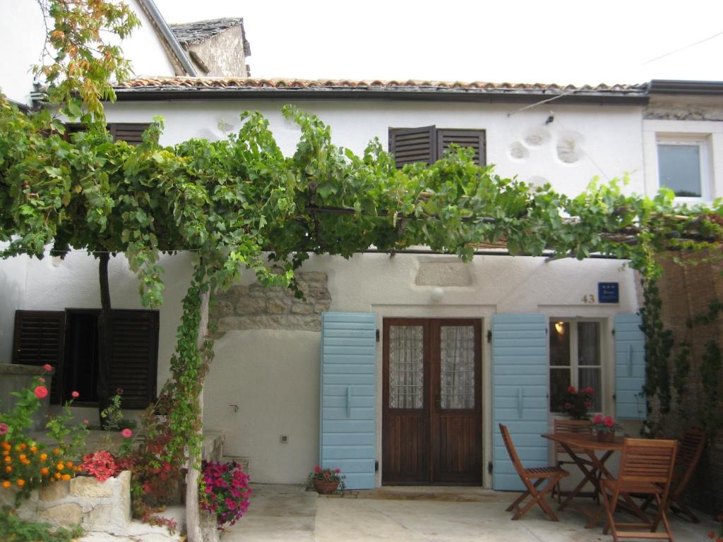 ein blau-weißes Haus mit einem Tisch und Stühlen in der Unterkunft Holiday Home Troštova Kuća in Pazin