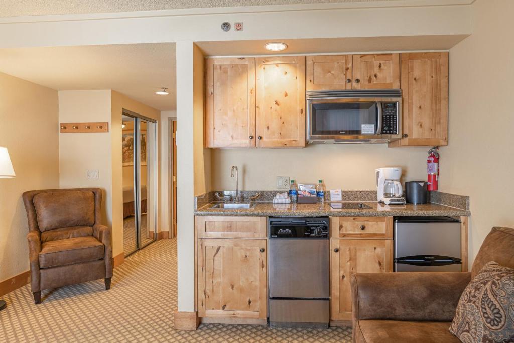 uma cozinha com armários de madeira e uma cadeira num quarto em Grand Lodge Condo in the Heart of Mt CB condo em Crested Butte