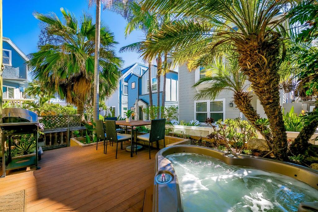 a deck with a hot tub and a table and palm trees at C-Ranch South in San Diego