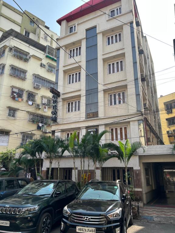 two cars parked in front of a building at Hotel Aston in Kolkata