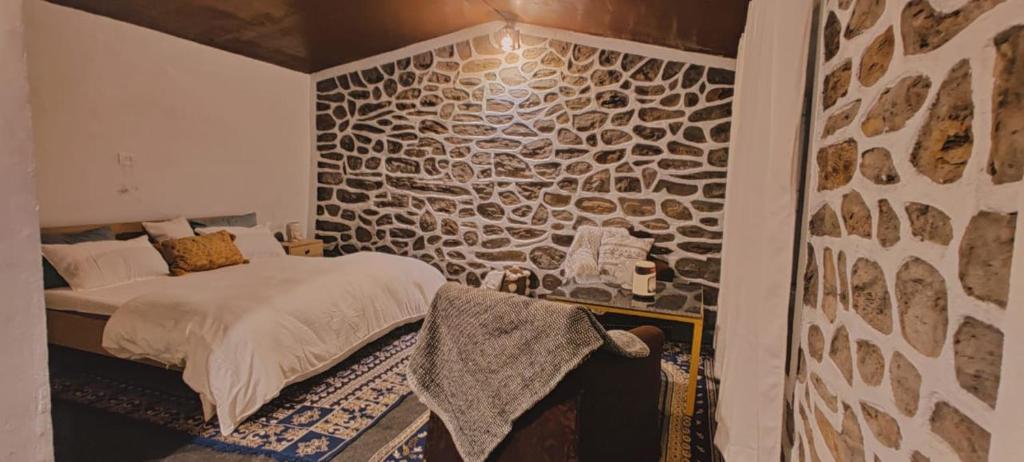 a bedroom with a stone accent wall and a bed at HimWanderer Camps & Cottages Pangot in Nainital