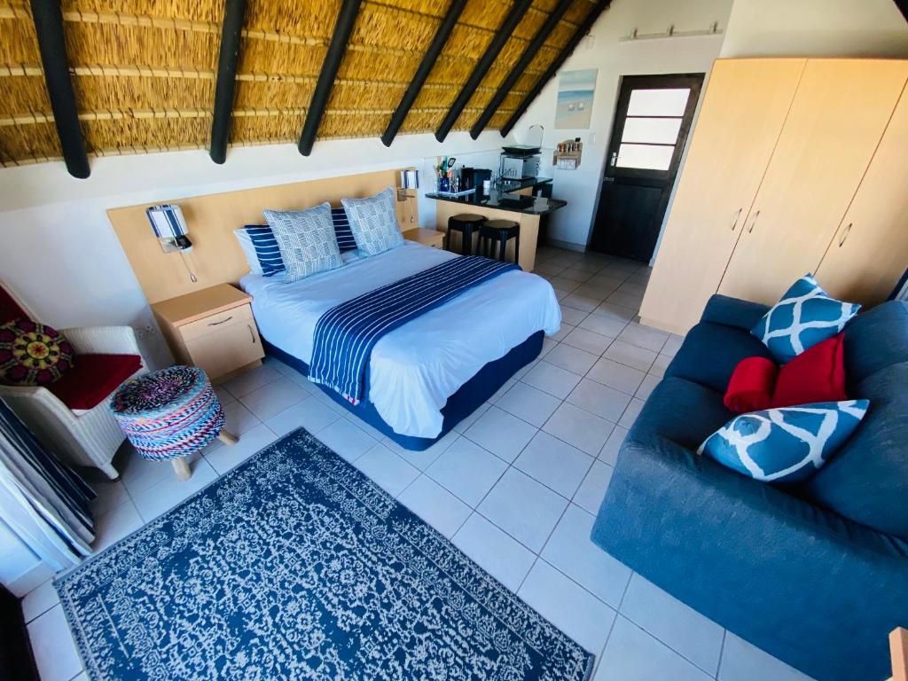 a bedroom with a bed and a blue couch at Shalom-self catering apartment in St Francis Bay