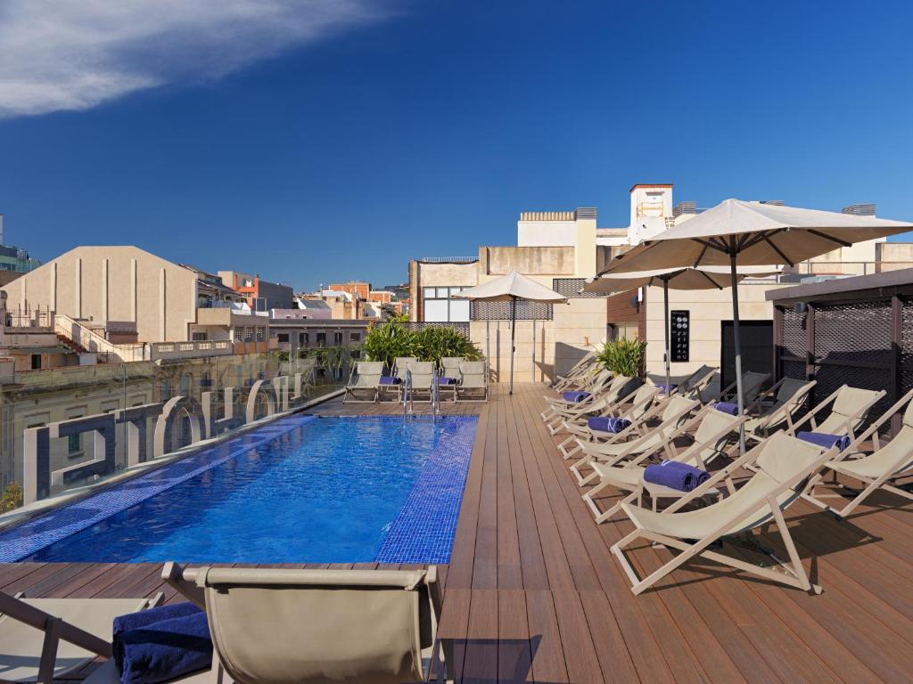 a row of lounge chairs and a swimming pool on a building at H10 Art Gallery 4* Sup in Barcelona