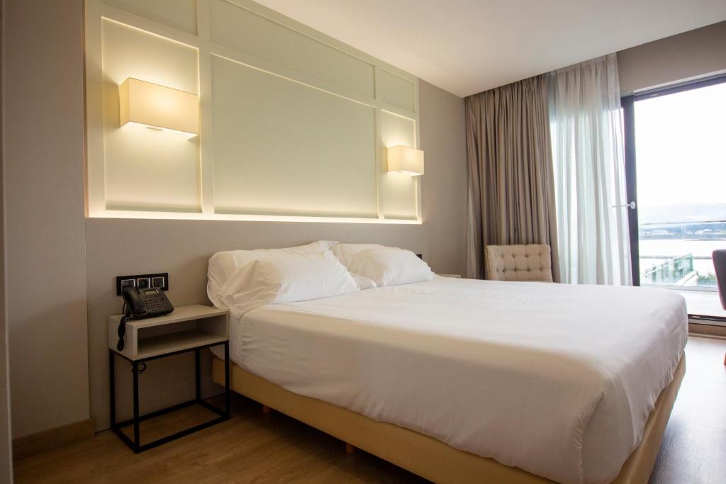 Una habitación de hotel con una cama y una ventana. en Oca Playa de Foz Hotel & Spa, en Foz