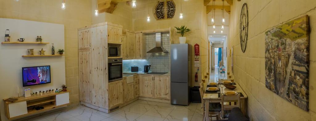 a kitchen with wooden cabinets and a refrigerator at Ta' Ġilard - Lovely Renovated Holiday Home in Żabbar