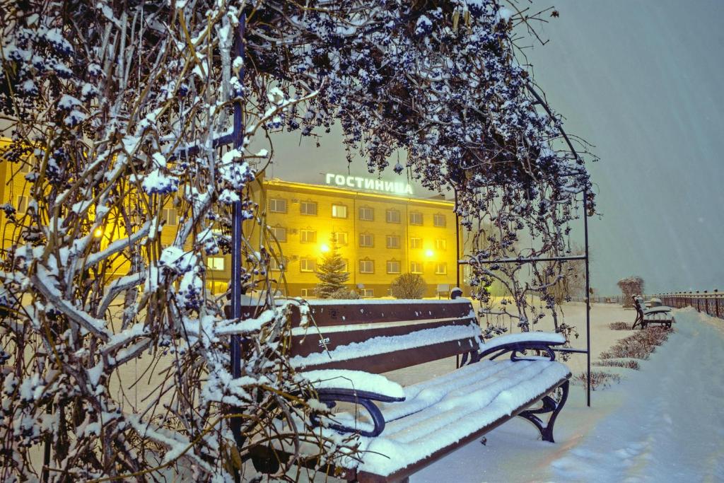VotkinskにあるZhemchuzhina Hotelの黄色い建物前の雪張りベンチ