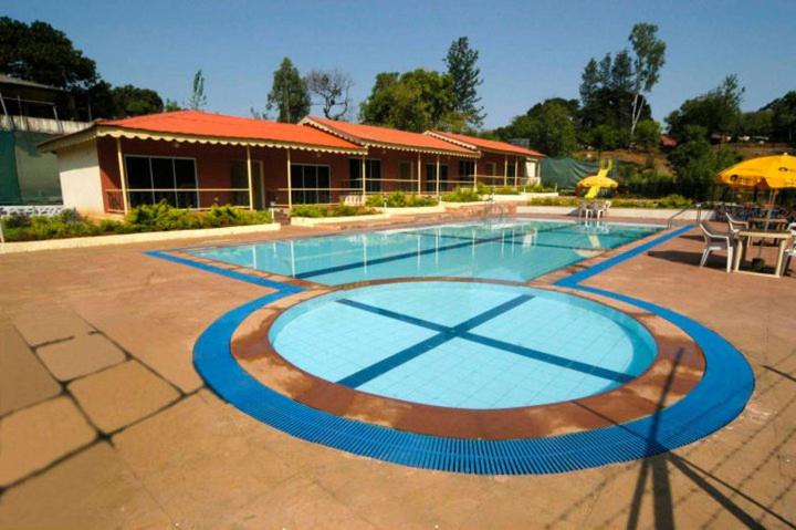 a large swimming pool in front of a building at Cold Spot Village Resort in Mahabaleshwar
