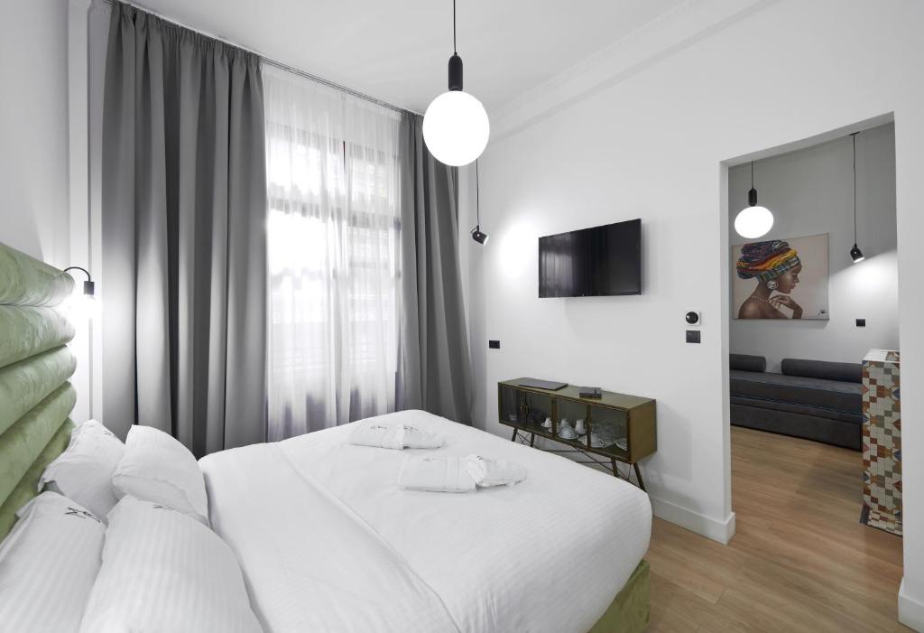 a white bedroom with a bed and a couch at The Maroon Bottle Hotel in Thessaloniki