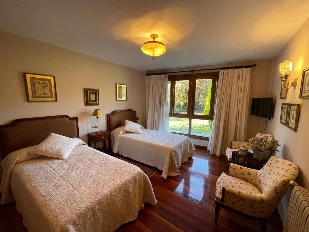 a bedroom with two beds and a chair and a window at Casa rural en entorno privilegiado 