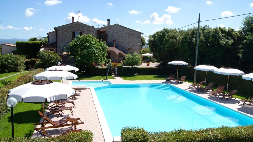 a swimming pool with chairs and umbrellas in front of a house at Casa Vacanze Ribocchi in Campiglia Marittima