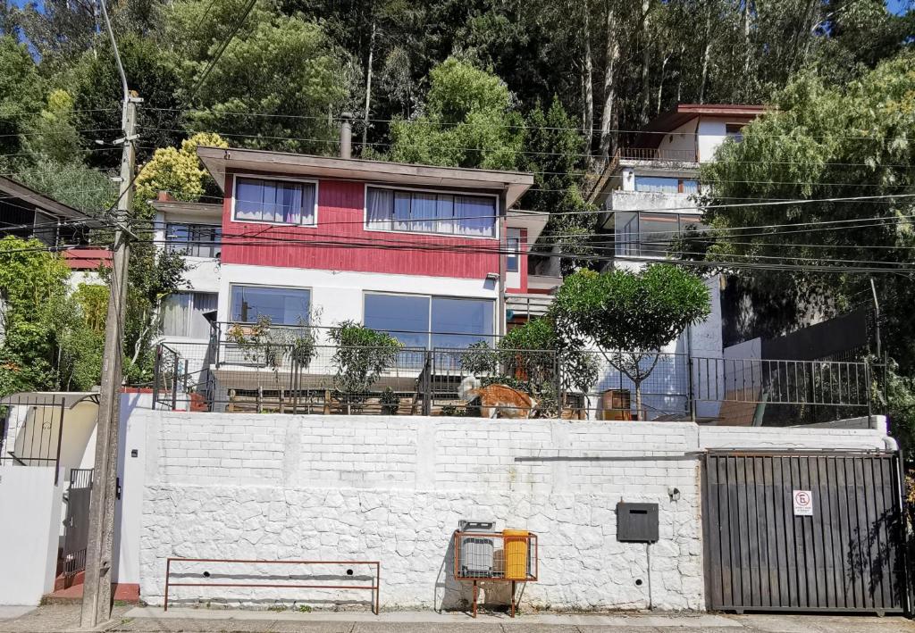 un edificio detrás de una pared blanca con una valla en Hostal Vivo Concepción, en Concepción