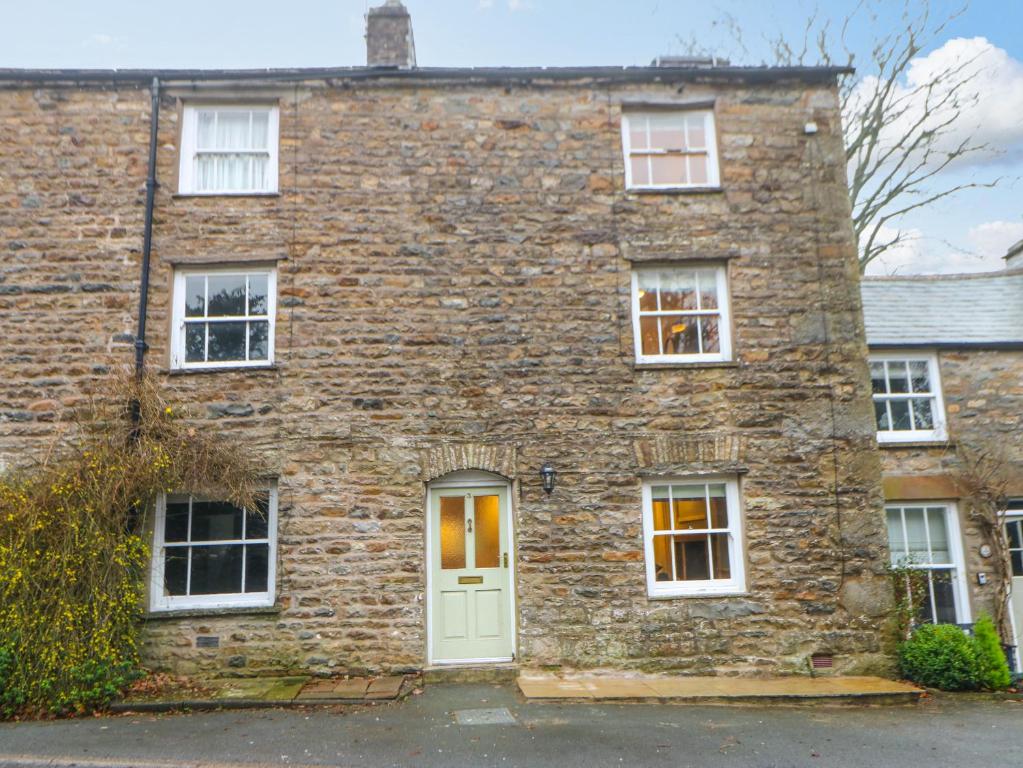 een oud bakstenen huis met een groene deur bij 3 Settlebeck Cottages in Sedbergh