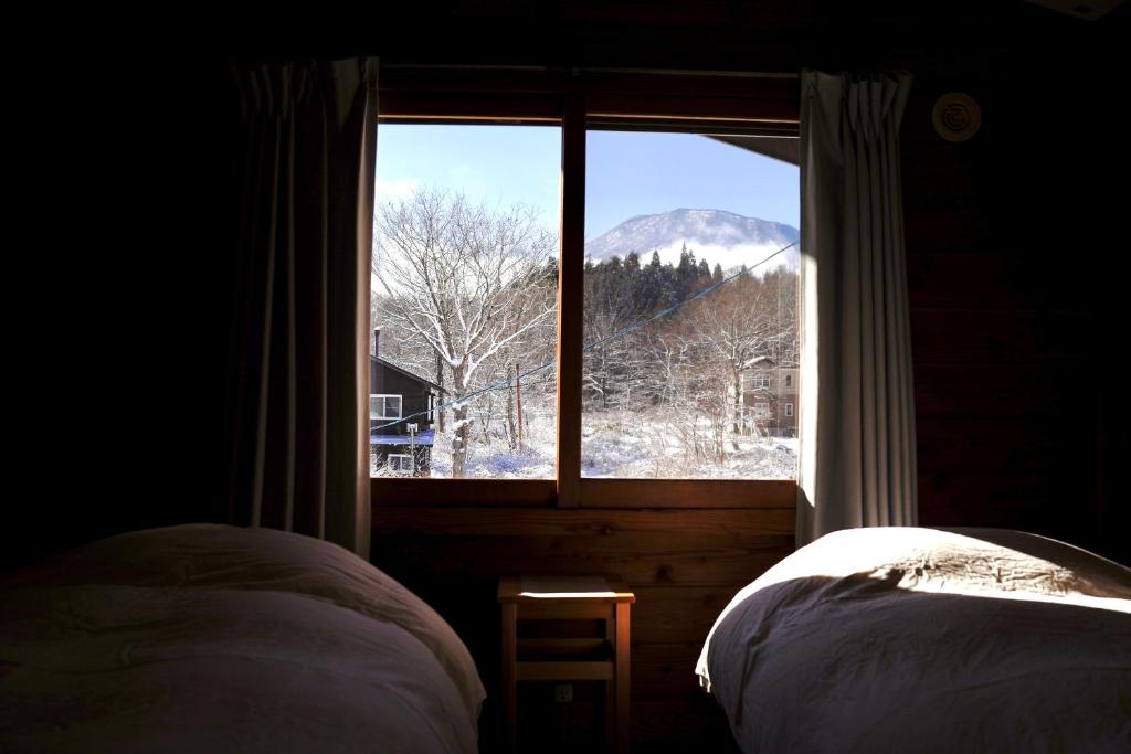 a bedroom with a window with a view of a mountain at björk （森の宿 ビヨルク） in Myoko