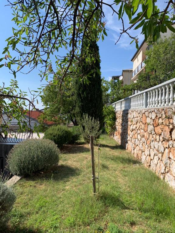 a tree in a yard next to a stone wall at Apartment Ivanka in Senj