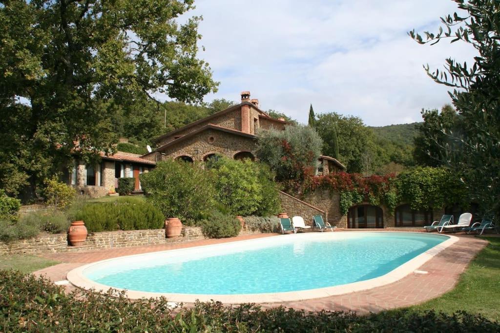 una grande piscina di fronte a una casa di Villa Pianelli ad Arezzo