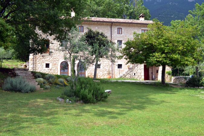 une grande maison en pierre dans un champ d'herbe dans l'établissement B&B Casal Cominium, à San Donato Val di Comino