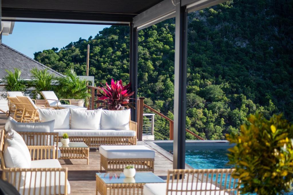 a patio with white furniture and a view of the water at Les villas de Sweet Hill in Saint Barthelemy
