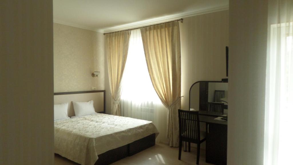a bedroom with a bed and a desk and a window at Royal Hotel in Kharkiv