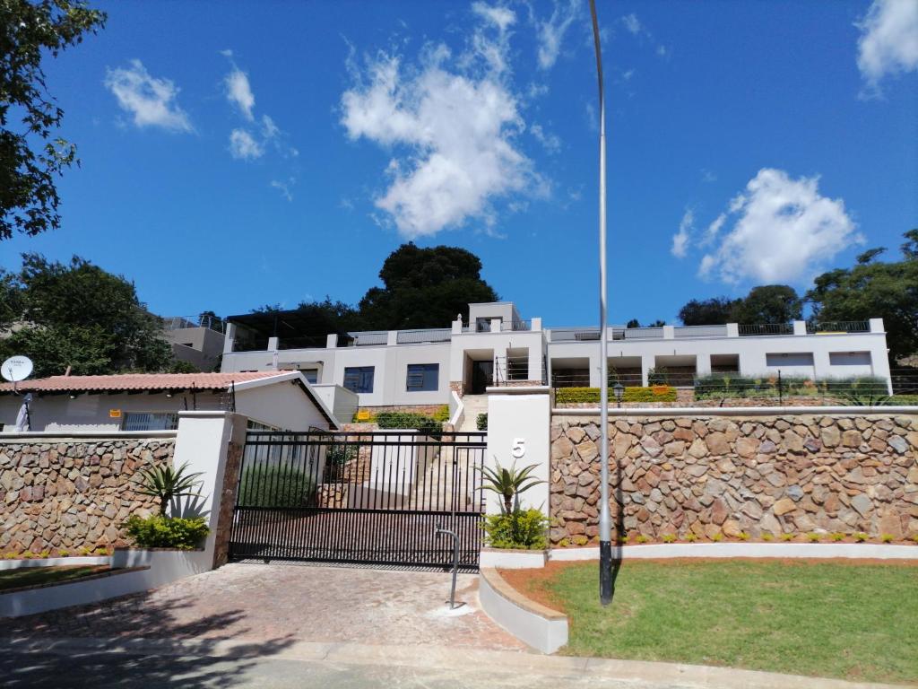 a white building with a fence and a stone wall at CityView, a stunning modern apartment in Johannesburg