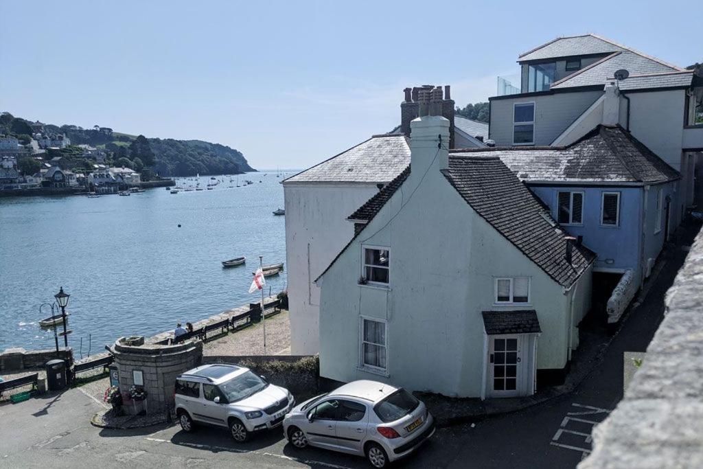 two cars parked in front of a building next to the water at Gulls Nest - Bijou Bolt Hole in Dartmouth