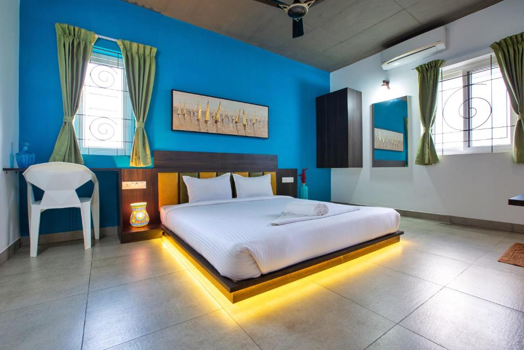 a bedroom with a bed and a blue wall at Sarvam Serviced Apartment in Coimbatore