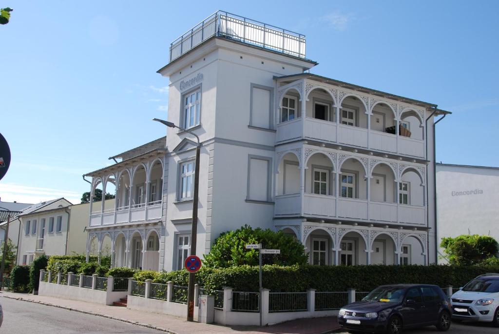 een wit gebouw met auto's ervoor geparkeerd bij Villa Concordia Binz - Cozy Apartment nur 50 Meter vom Strand in Binz