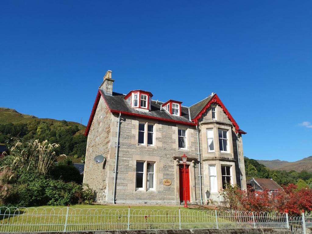ein altes Steinhaus mit einer roten Tür in der Unterkunft Tayview in Killin