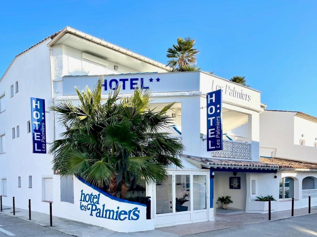 a hotel with a palm tree in front of it at Hotel Les Palmiers En Camargue in Saintes-Maries-de-la-Mer