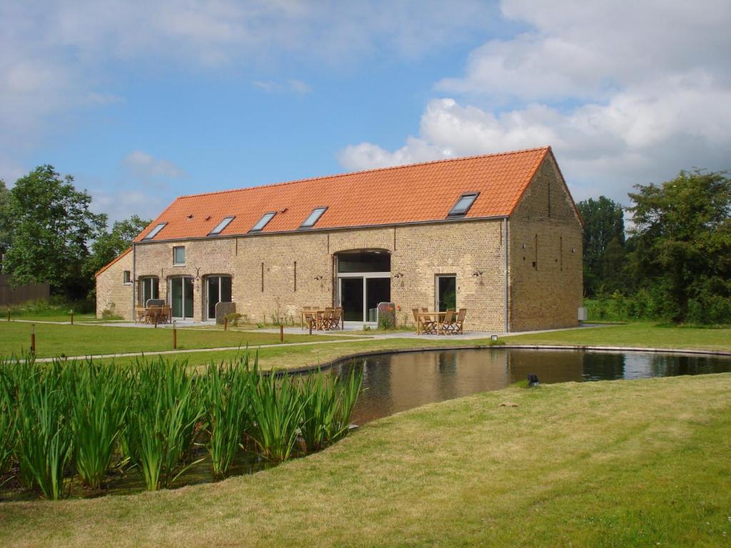 ein großes Backsteingebäude mit einem Teich davor in der Unterkunft Hoeve De Hagepoorter in Jabbeke