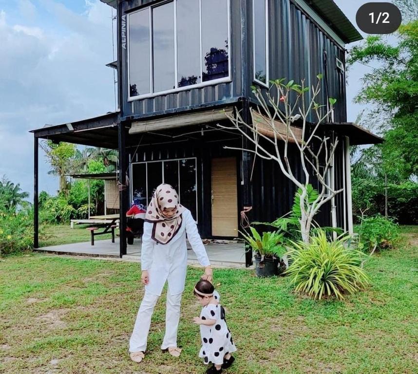 a person in a costume with a dog in front of a house at Hasina Resort @Sedili in Kampong Bukit Lintang