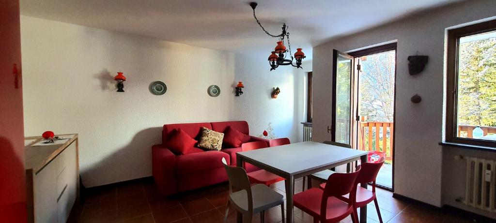ein Wohnzimmer mit einem roten Sofa und einem Tisch in der Unterkunft Mont Blanc Apartment- Bluchalet in Courmayeur