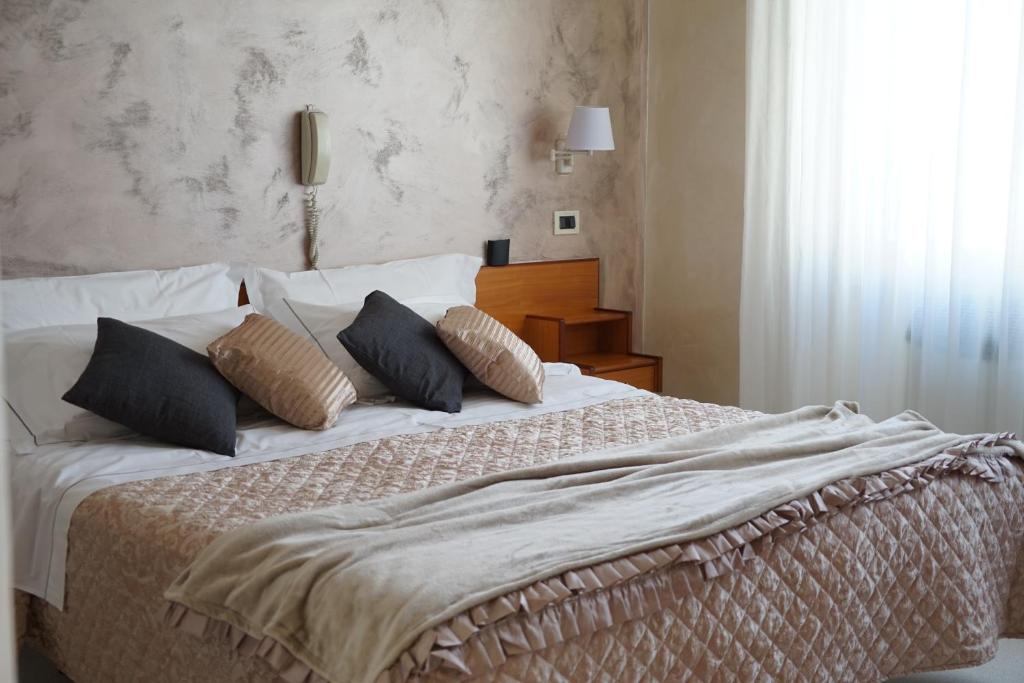 a bed with a white comforter and pillows at Hotel Marconi in Fiuggi
