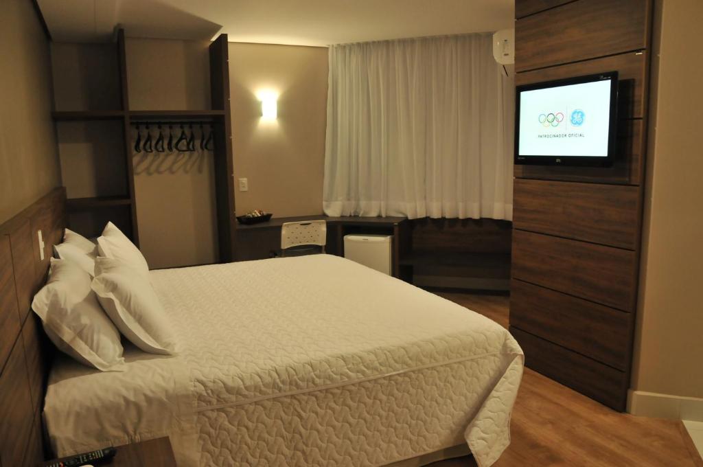Poente Hotel في São Lourenço do Oeste: غرفة فندقية بسرير وتلفزيون بشاشة مسطحة