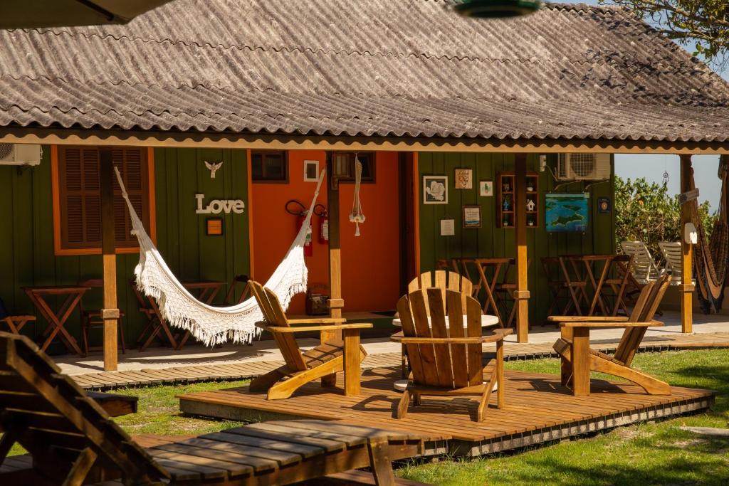 a house with chairs and a hammock in front of it at Pousada Kainoa in Ilha do Mel