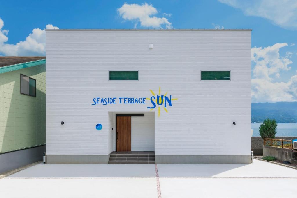 um edifício branco com um sinal que lê o triângulo de serviço sol em SEASIDE TERRACE SUN - Vacation STAY 12430 em Numazu