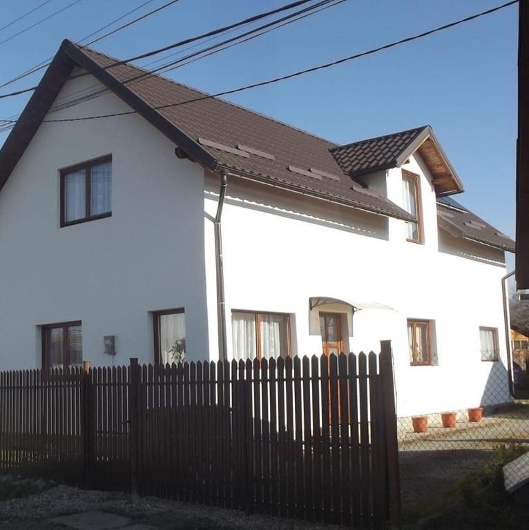 a white house with a fence in front of it at Casa Mocanu in Sărmaş