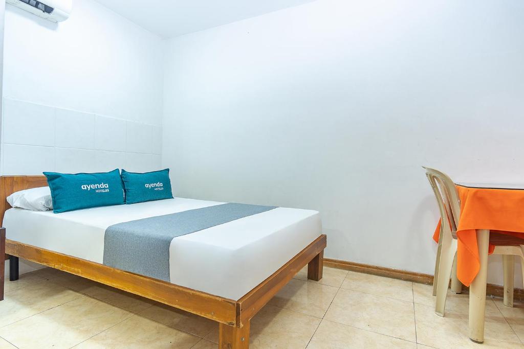 Una cama con dos almohadas azules encima. en Ayenda Santander, en Neiva