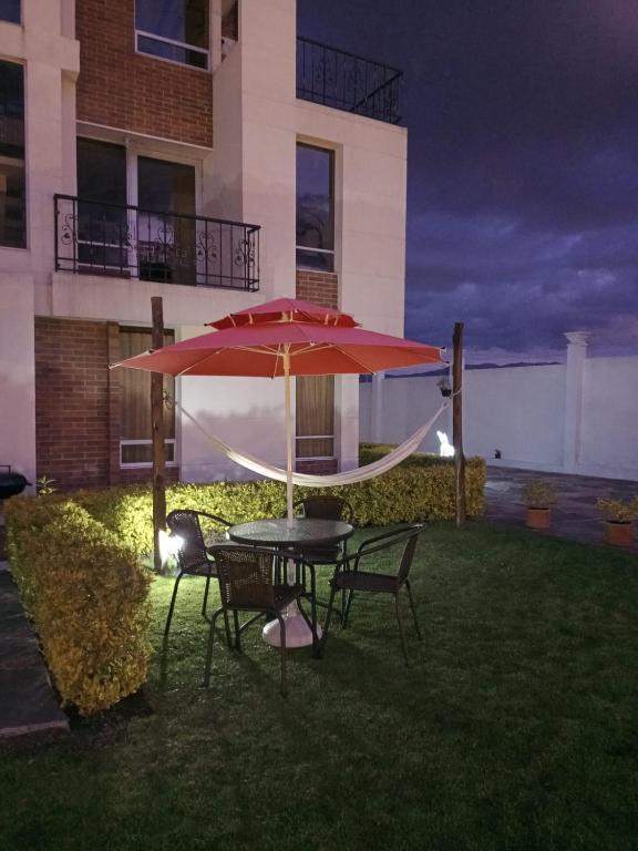 a table and chairs under an umbrella in a yard at Valle De Iraka - Apartahotel in Tibasosa