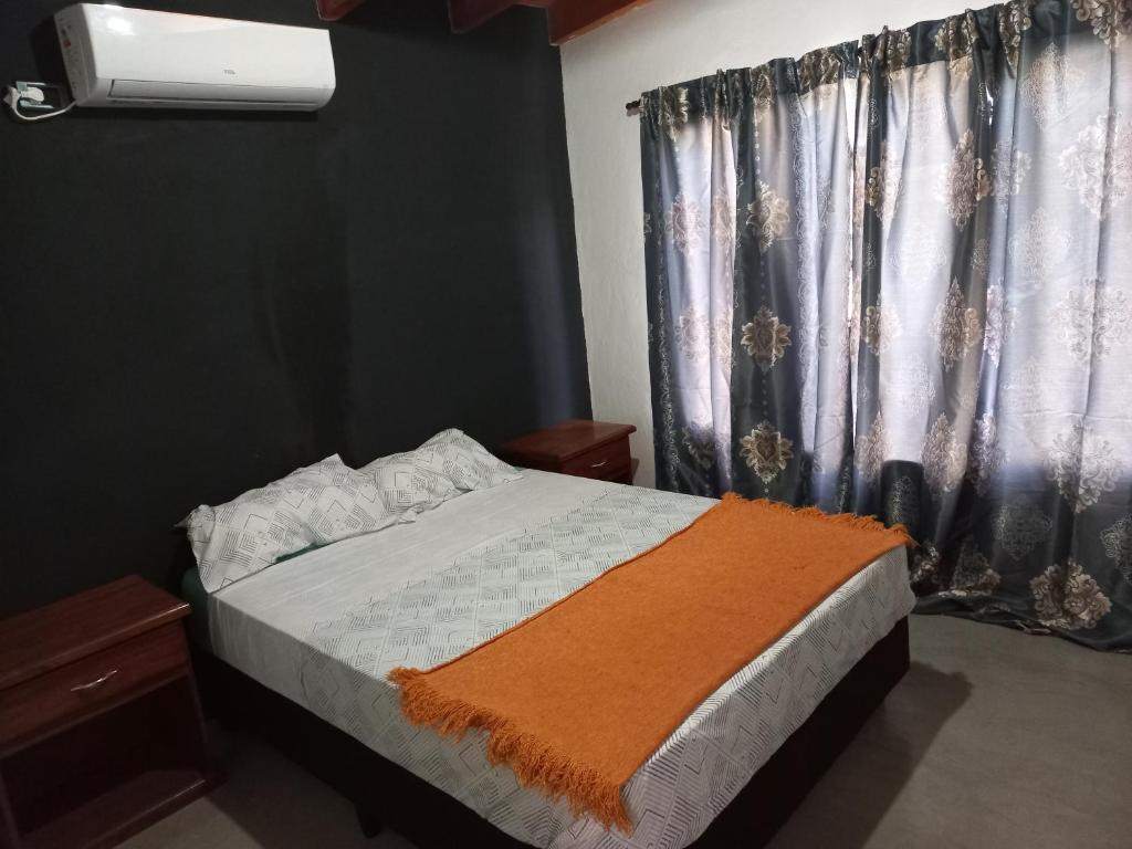 Un dormitorio con una cama con una manta naranja. en Quinta La Encantada en San Ignacio